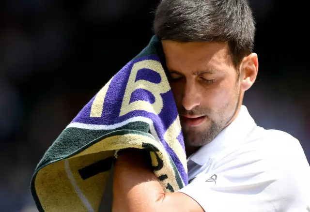 Novak Djokovic wipes his face with a towel