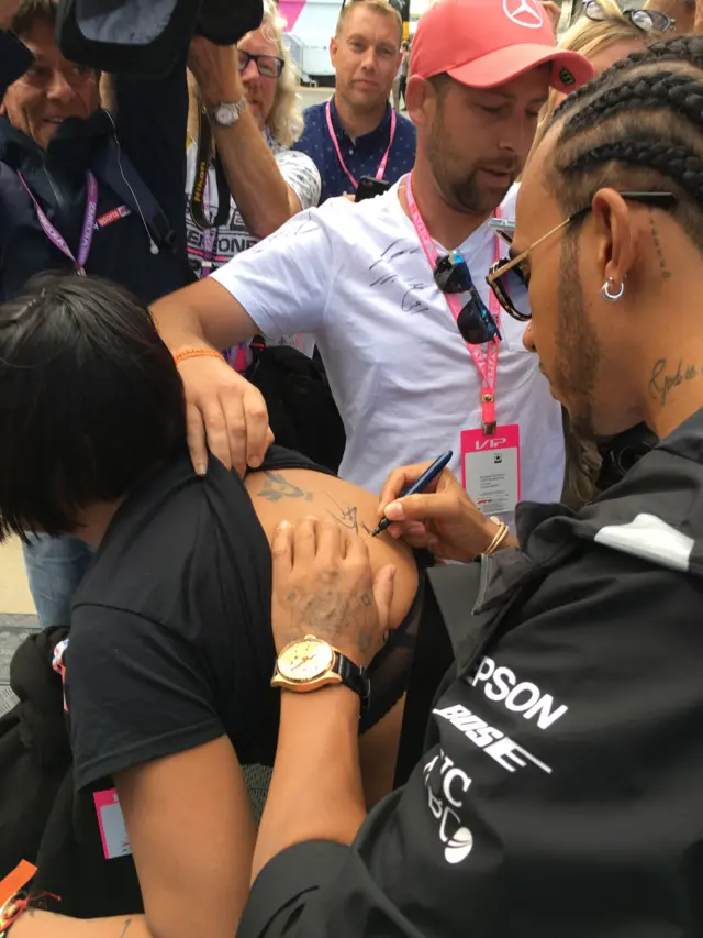 Lewis Hamilton signs a fan's back