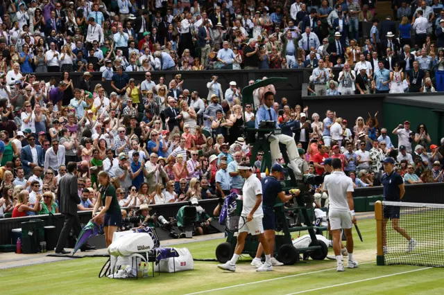 The crowd rise to their feet to applaud after Roger Federer takes the game into a fifth set