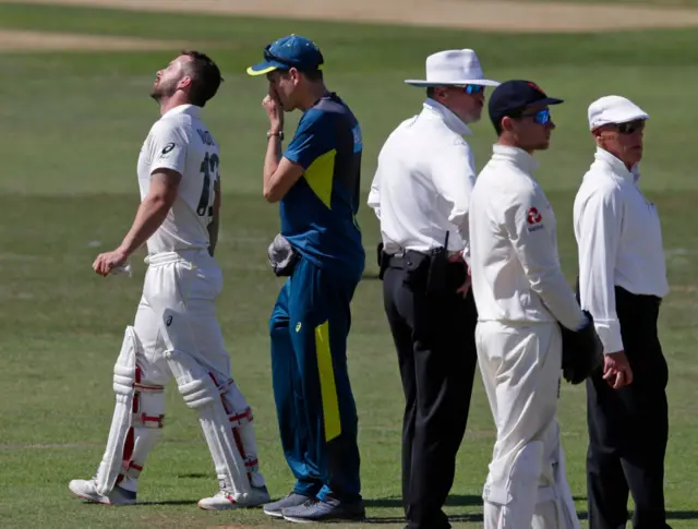 Matthew Wade (left) walks off after being hit by the ball during the Australian XI's match with the England Lions