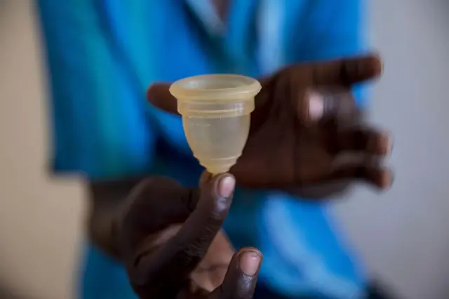 A health worker holding a menstrual cup