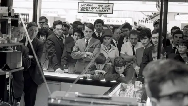 Crowds gather around a television set