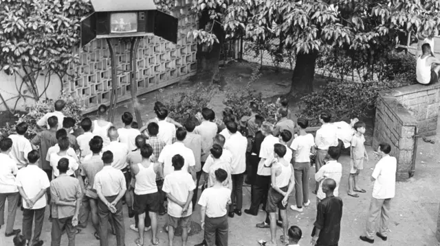 People in a park watching TV