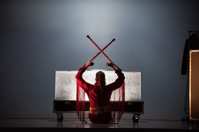 A performer holding glittering crutches on stage