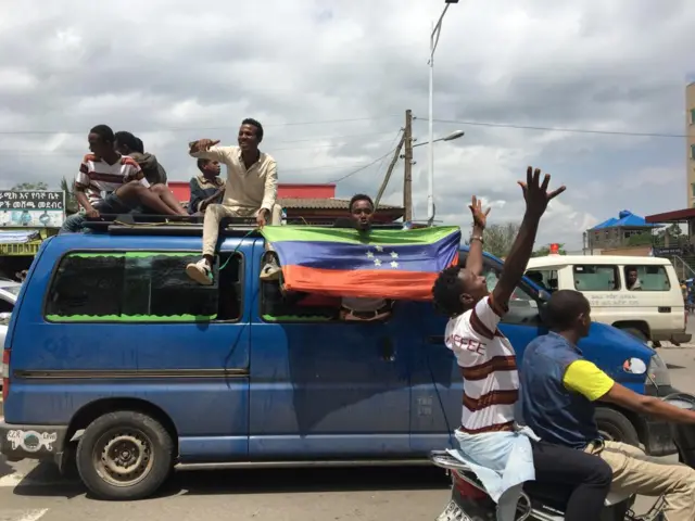 People waving a flag from a van