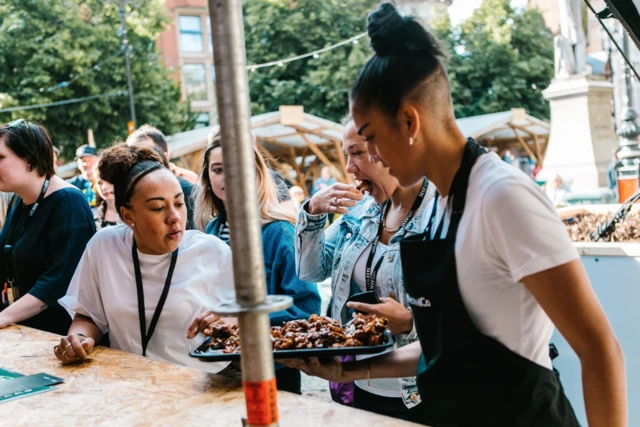 A Festival Square chef handing out a tray of food