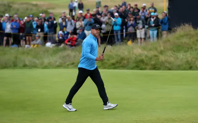 Brooks Koepka raises his putter in acknowledgement of the crowd on the 17th