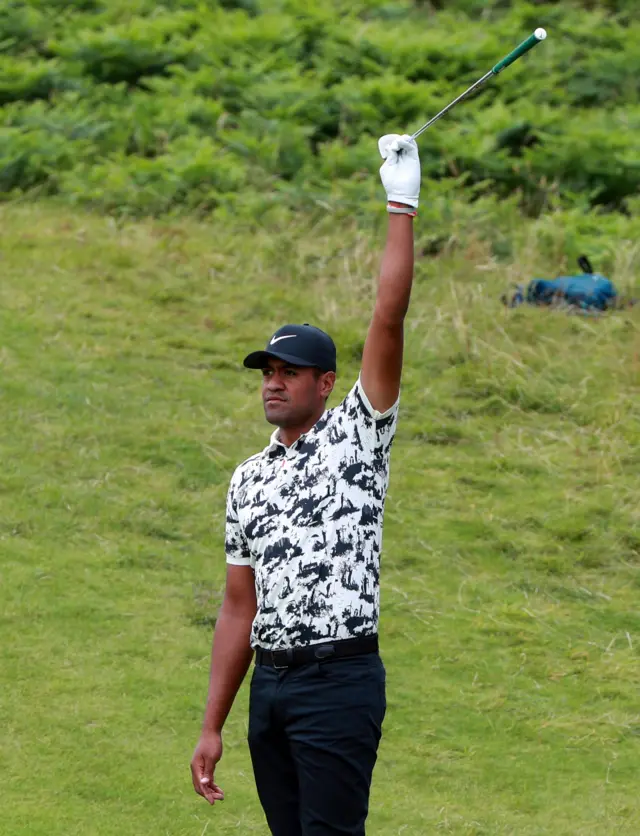 Tony Finau raises his club to acknowledge the crowd after holing a shot from off the green