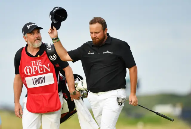 Shane Lowry takes off his cap to accept the applause of spectators as he walks up the 18th fairway
