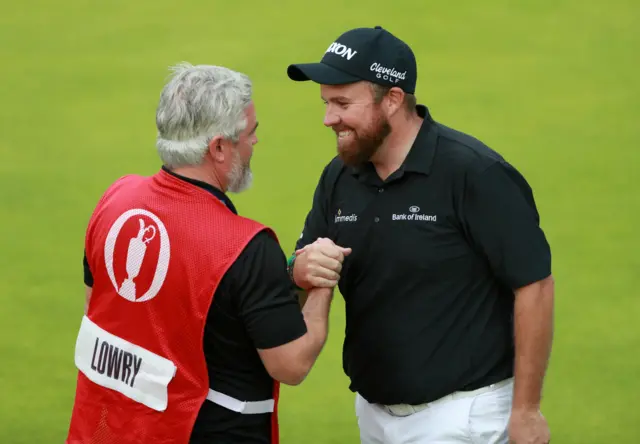 Shane Lowry shares a joke with his caddie on the 18th green