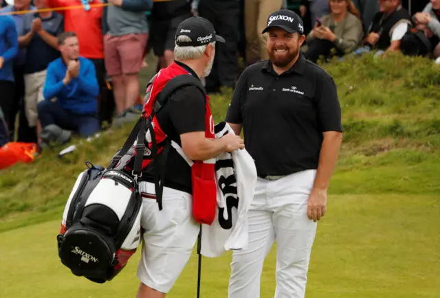 Shane Lowry smiles with his caddie on the 10th green