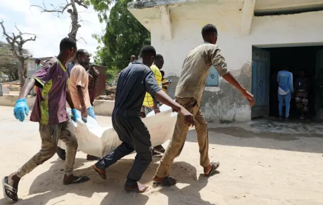 Relatives carry the dead body of a civilian killed in an explosion outside a hotel near the international airport in Mogadishu on 22 July 2019.