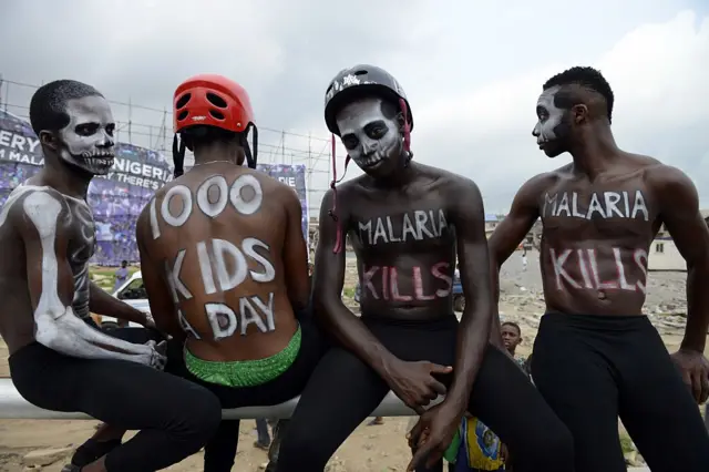 People wil signs painted on them saying 'malaria kills'