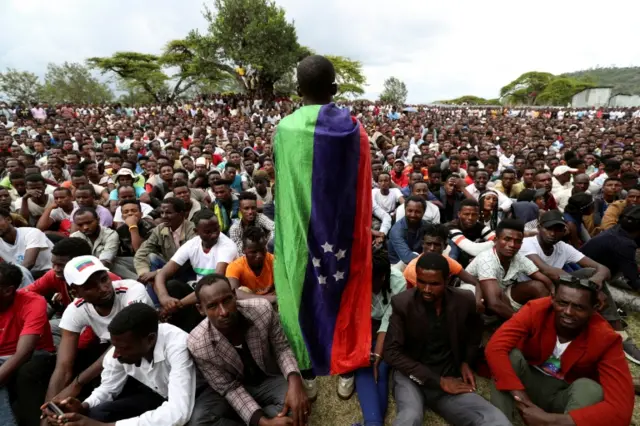 A Sidama youth leader carrying a flag addresses people as they gather for a meeting to declare their own region in Hawassa