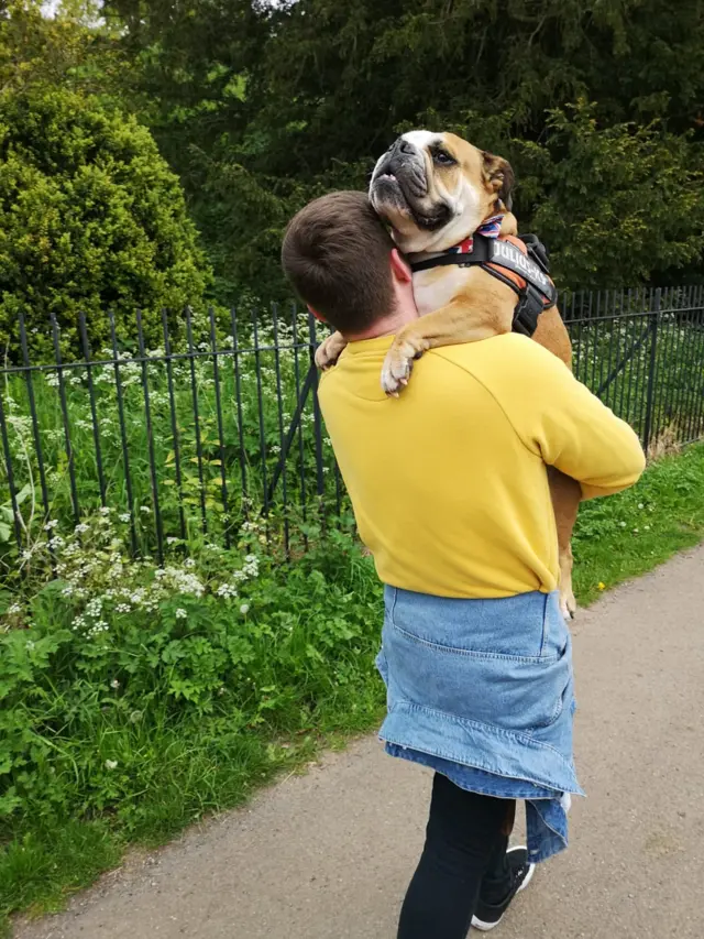 Man carries a dog