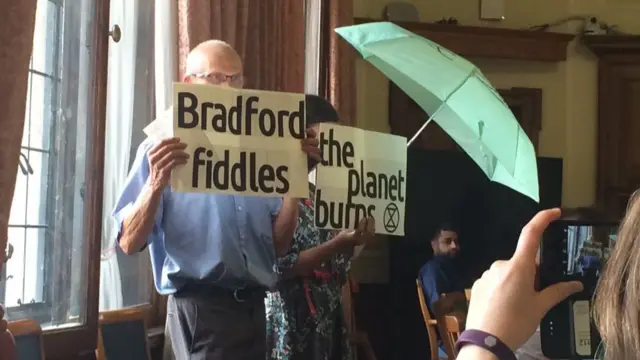 Protesters at the meeting holding signs