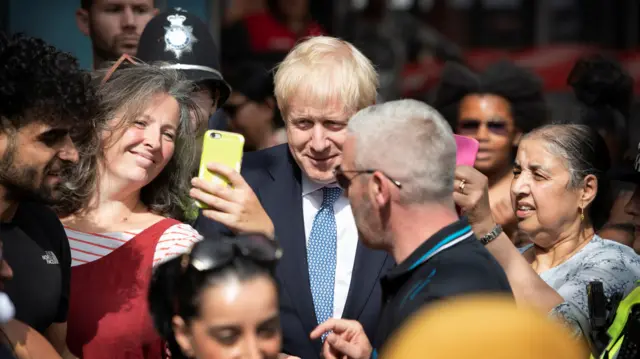 Women take pictures of Britain"s Prime Minister Boris Johnson as he visits Birmingham