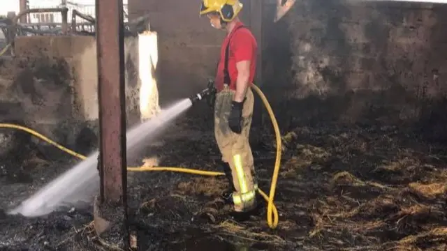 Firefighter spraying water inside barn