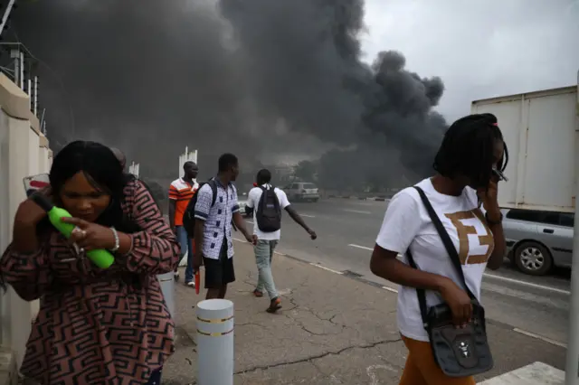 People walk past a fire service station in Abuja set ablaze during a protest on 22 July in which IMN members clashed with police.