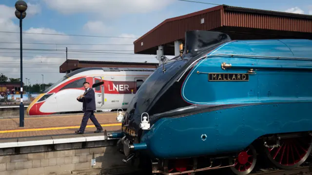 Steam traction inspector Jim Smith is pictured with a new Azuma train standing alongside the Mallard steam locomotive at York Station