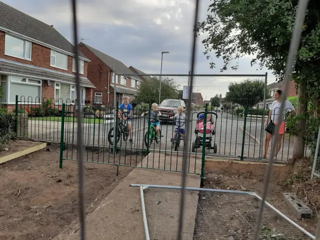 Children look at the space where the hedge used to be