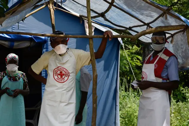 Ebola health workers pictured by a tent where treatments are administered.