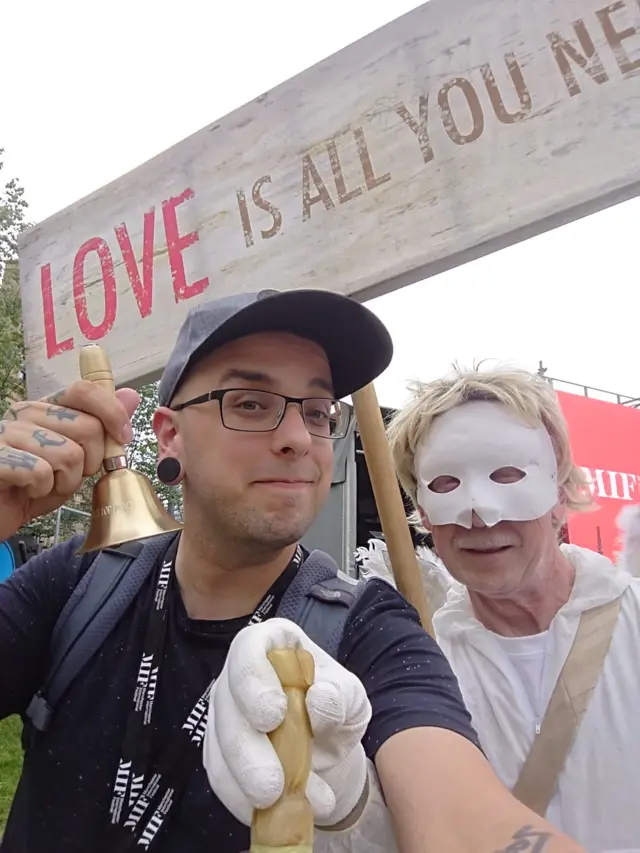 Dan Hett and a man with a mask holding a bell