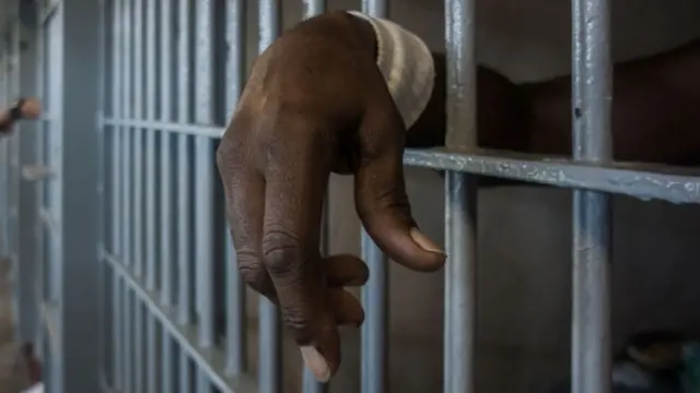 A prisoner's hangs his had through the bars of his cell door