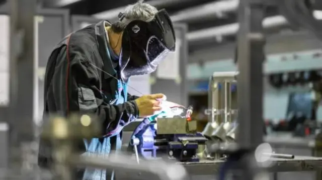 man in  mask working at a machine