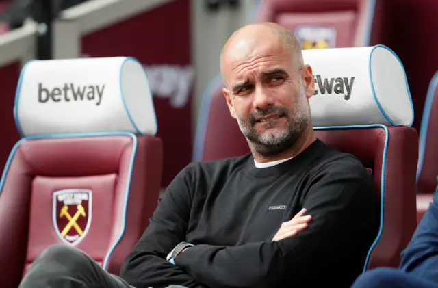 Pep Guardiola takes his seat in the dugout