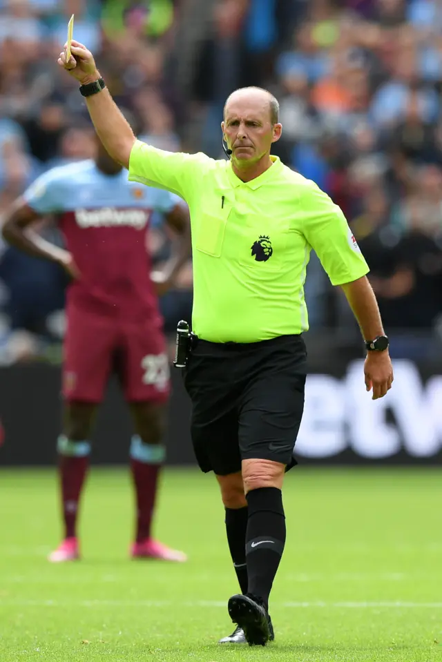 Mike Dean shows a yellow card