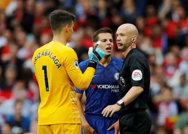 Referee Anthony Taylor  is surrounded by Chelsea players after awarding a penalty to Manchester United