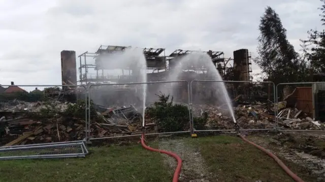 Hoses spraying water on the building after the fire