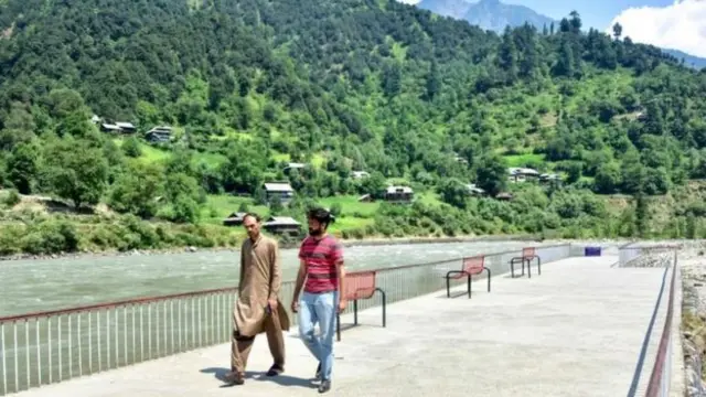 Kashmiri men walk by a river near the Line of Control, the de facto border between Pakistan and India