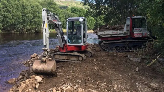 A mini digger clearing the river