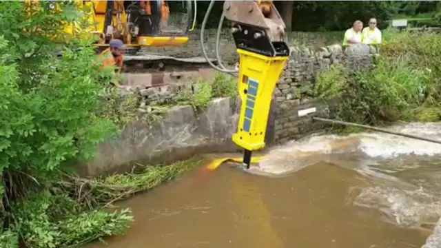 A weir being removed by machinery