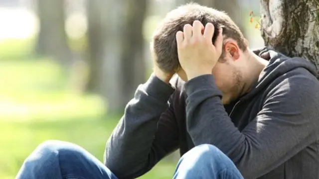 Man leaning against tree