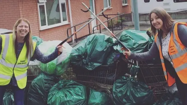 Two members of the group with bin bags of rubbish