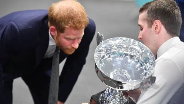 Prince Harry checks out trophy at half time