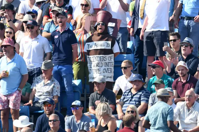 A fan, dressed as the Ashes trophy (C), reacts on the fourth day of the third Ashes cricket Test match between England and Australia at Headingley