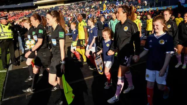 Players, officials and mascots walk out at Hampden