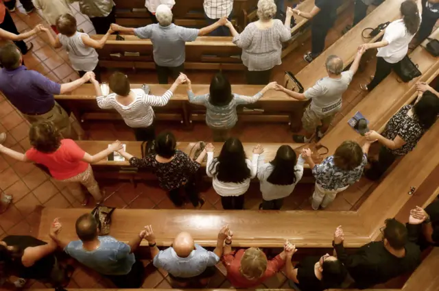 People hold hands in St Pius X Church at a vigil