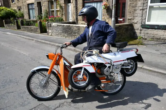 Man on scooter with another in his hand