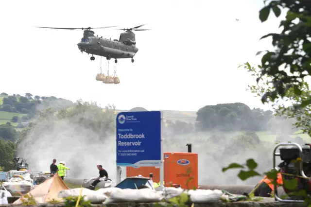 A Royal Air Force Chinook transports sandbags as work continues to shore up the dam at Toddbrook Reservoir