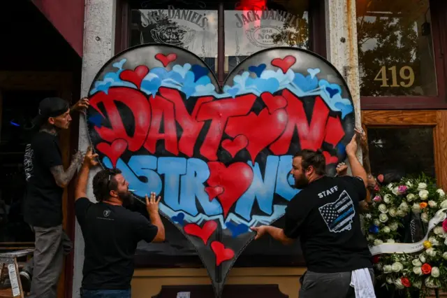 Men hang a metal-fabricated "Dayton Strong" sign on the front of Ned Pepper's Bar at the site where Dayton mass shooting gunman Connor Betts was gunned down