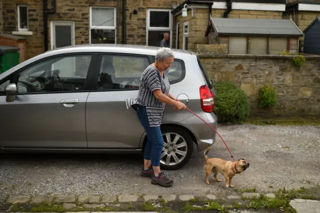 A woman walks her dog in Whaley Bridge as residents are allowed home