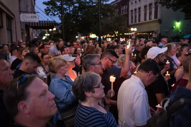 People take part of a candle lit vigil in honor of those who lost their lives or were wounded in a shooting in Dayton, Ohio on August 4, 2019. -