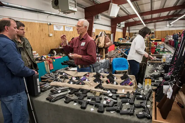 A licensed dealer performs a background check on a buyer during a gun show in Montana