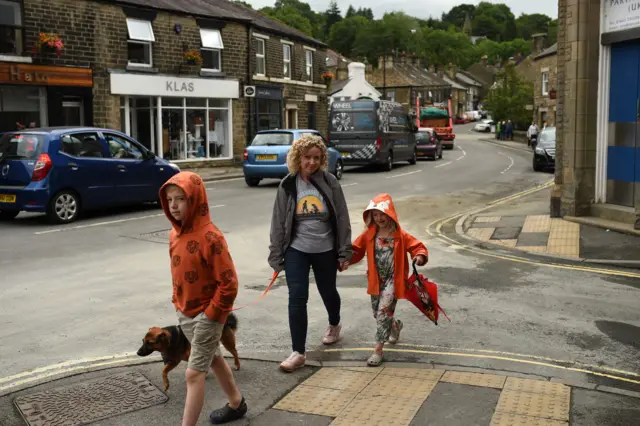 A woman walks her dog in Whaley Bridge after resident return home