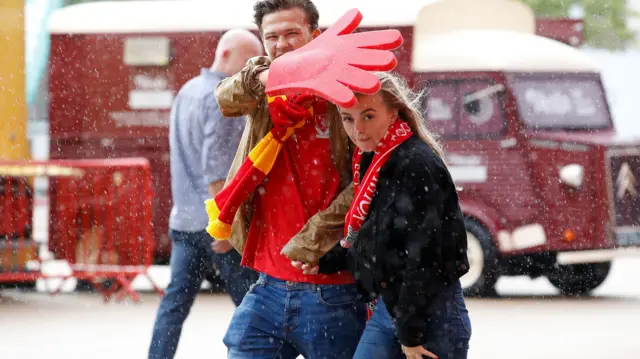 Liverpool fans get caught in a shower on the way to Anfield